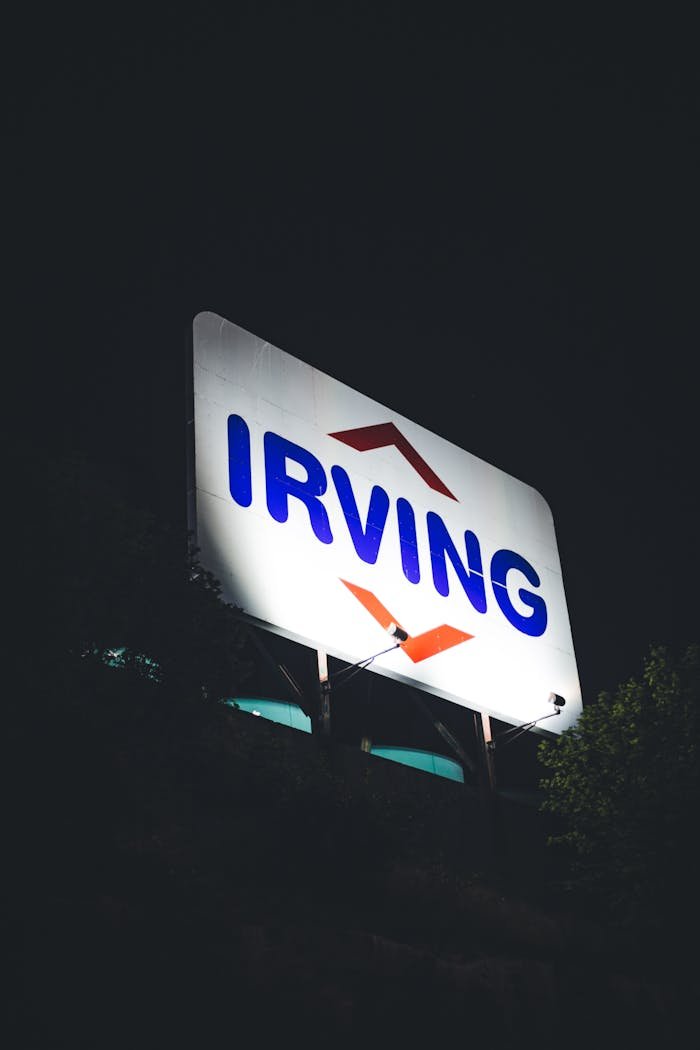 services-04 Close-up of a large illuminated Irving sign against a dark night sky.