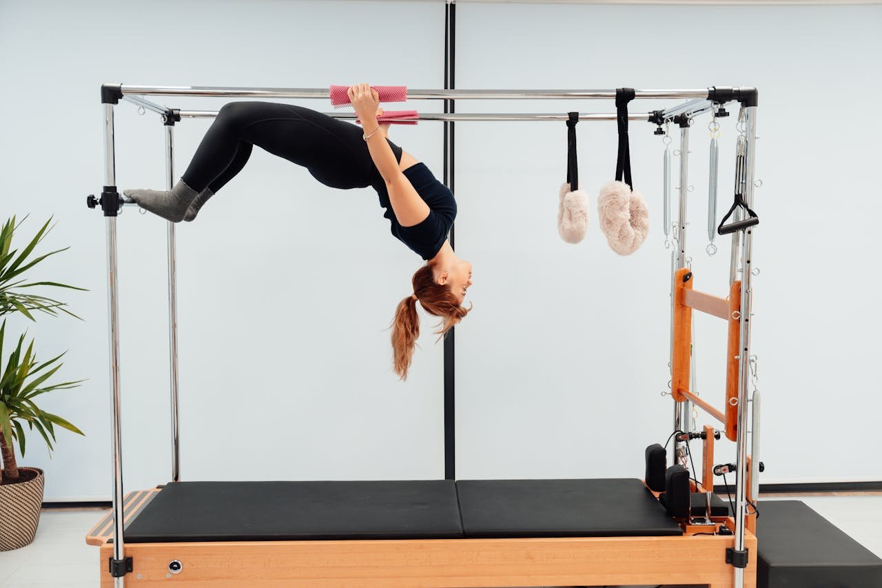 services-img-01 A woman engaging in a Pilates routine on a Reformer machine, showcasing strength and flexibility.