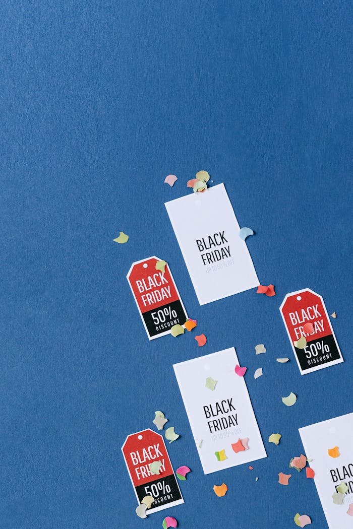 about-img-01 Colorful sale tags and confetti on a textured blue surface for Black Friday deals.